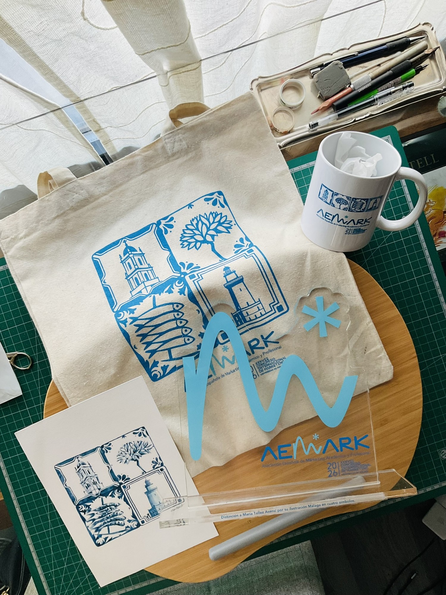 Tote bag, taza y láminas con Málaga en cuatro símbolos, la obra de María Téllez para el congreso AEMARK 2026