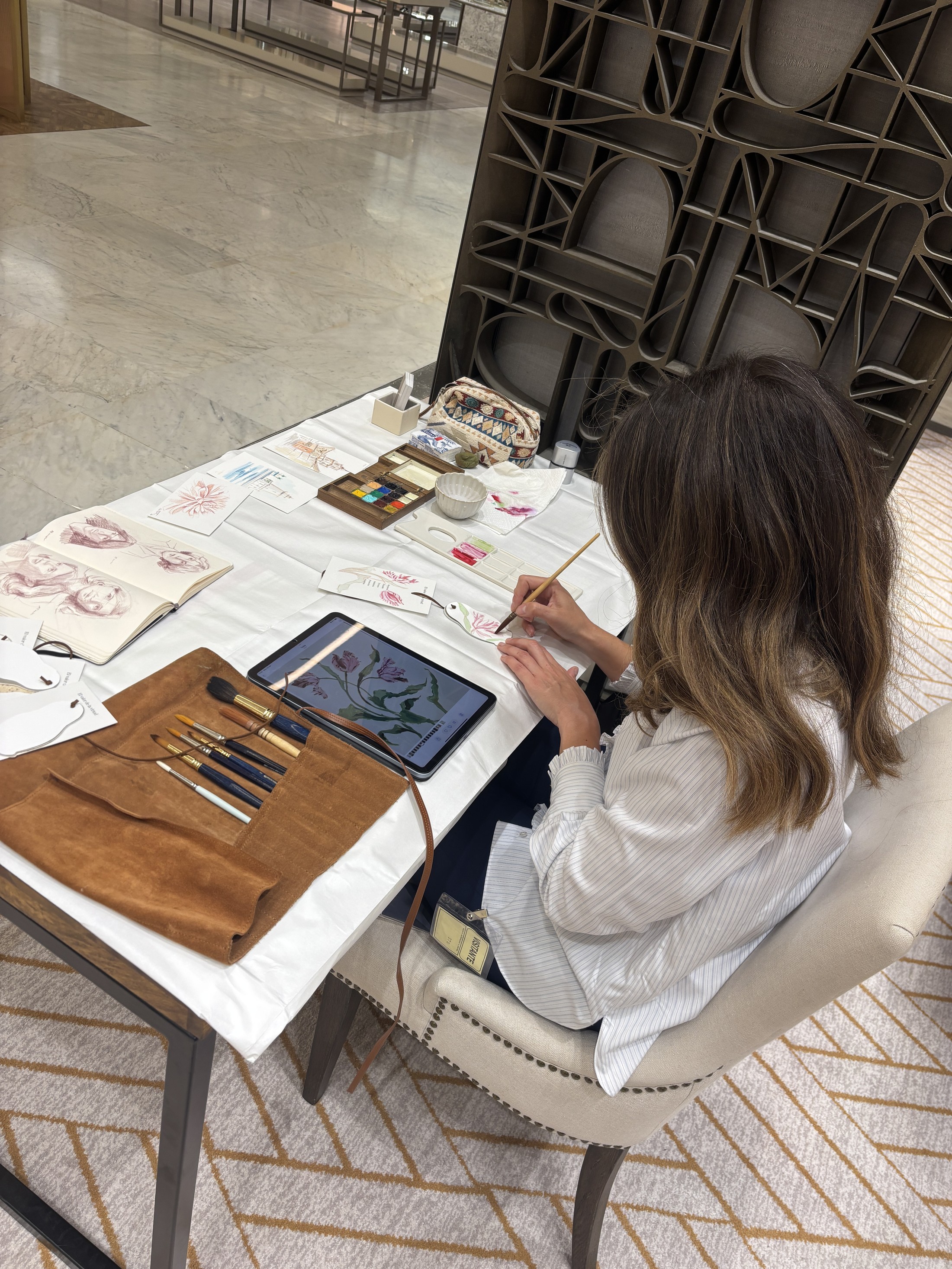 María Téllez pintando en directo en una mesa con acuarelas dentro de la joyería Suárez