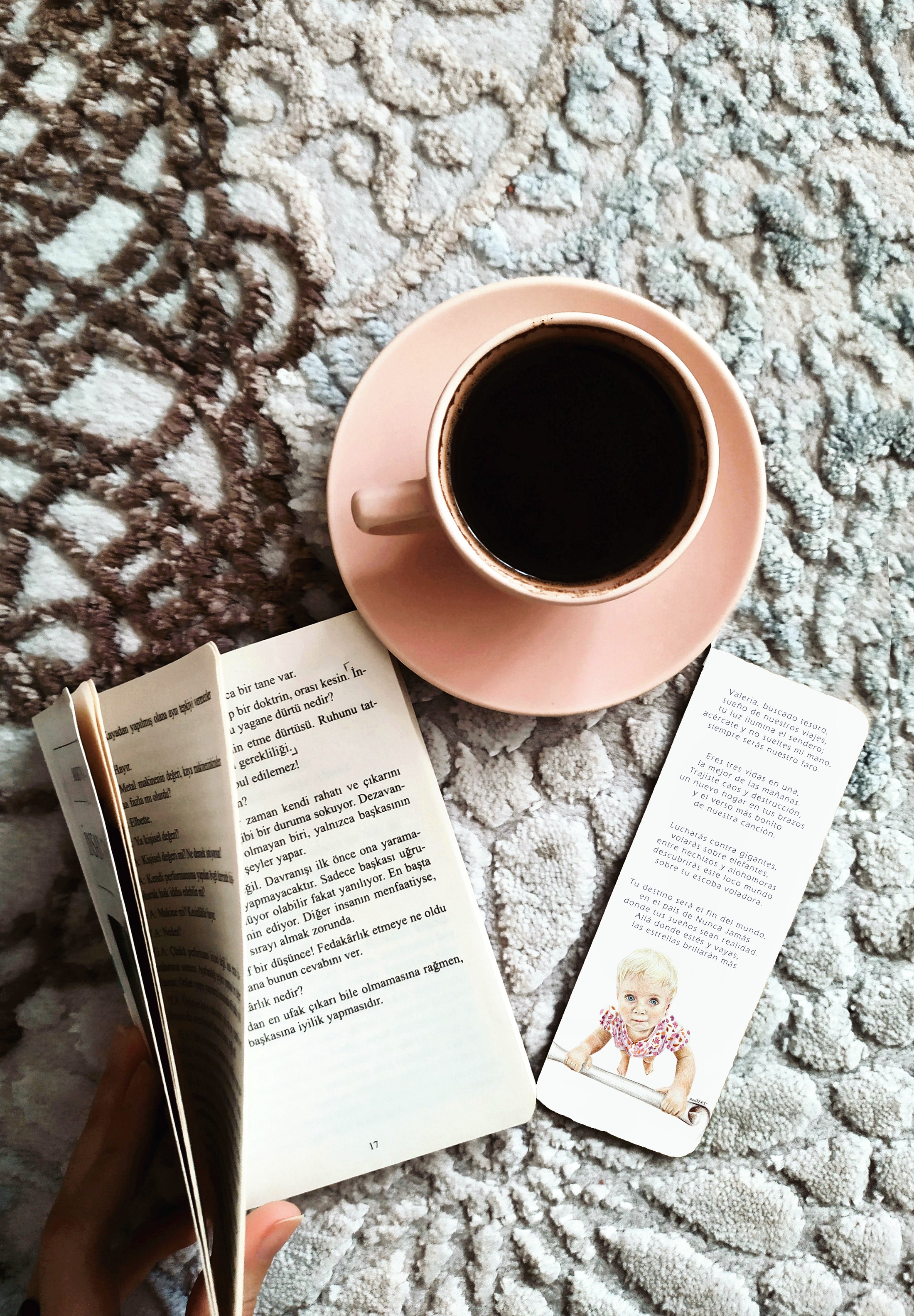 Marcapáginas de bautizo con la ilustración de un bebé, sobre un libro abierto junto a un café