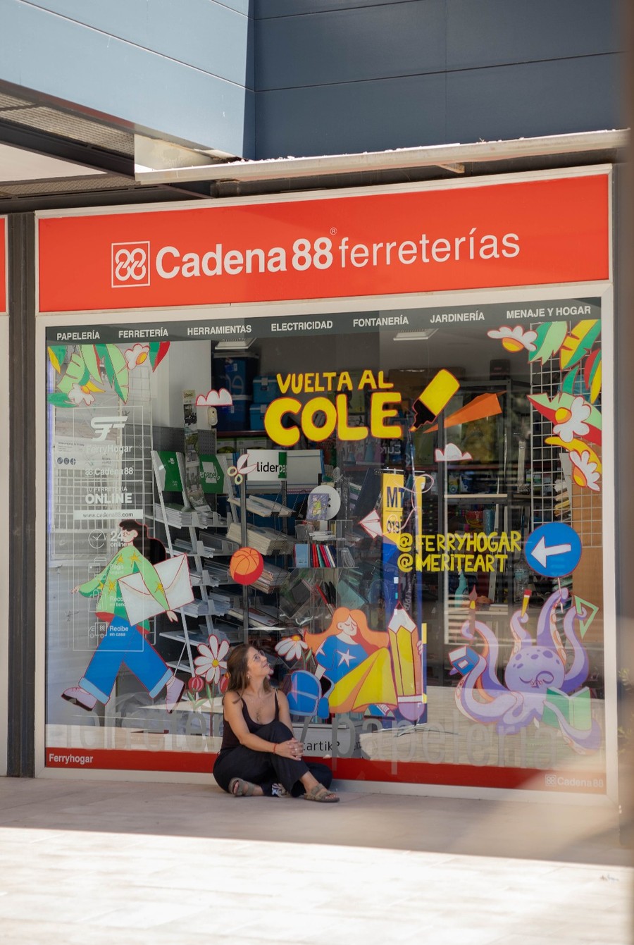 Escaparate ilustrado de «Vuelta al cole» para una ferretería, con María Téllez sentada delante