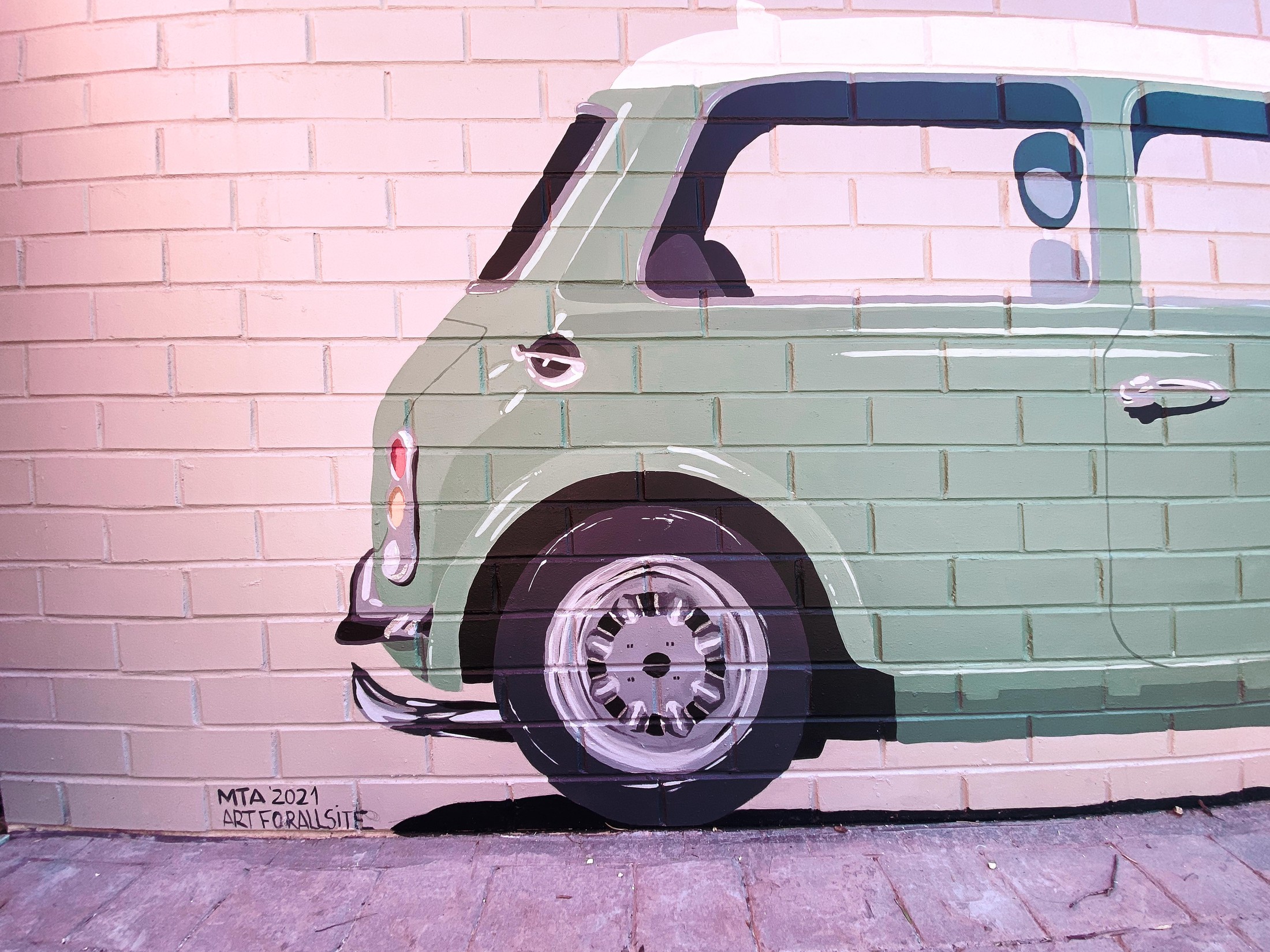 Mural de un Mini clásico verde pintado a tamaño real sobre una pared de ladrillo