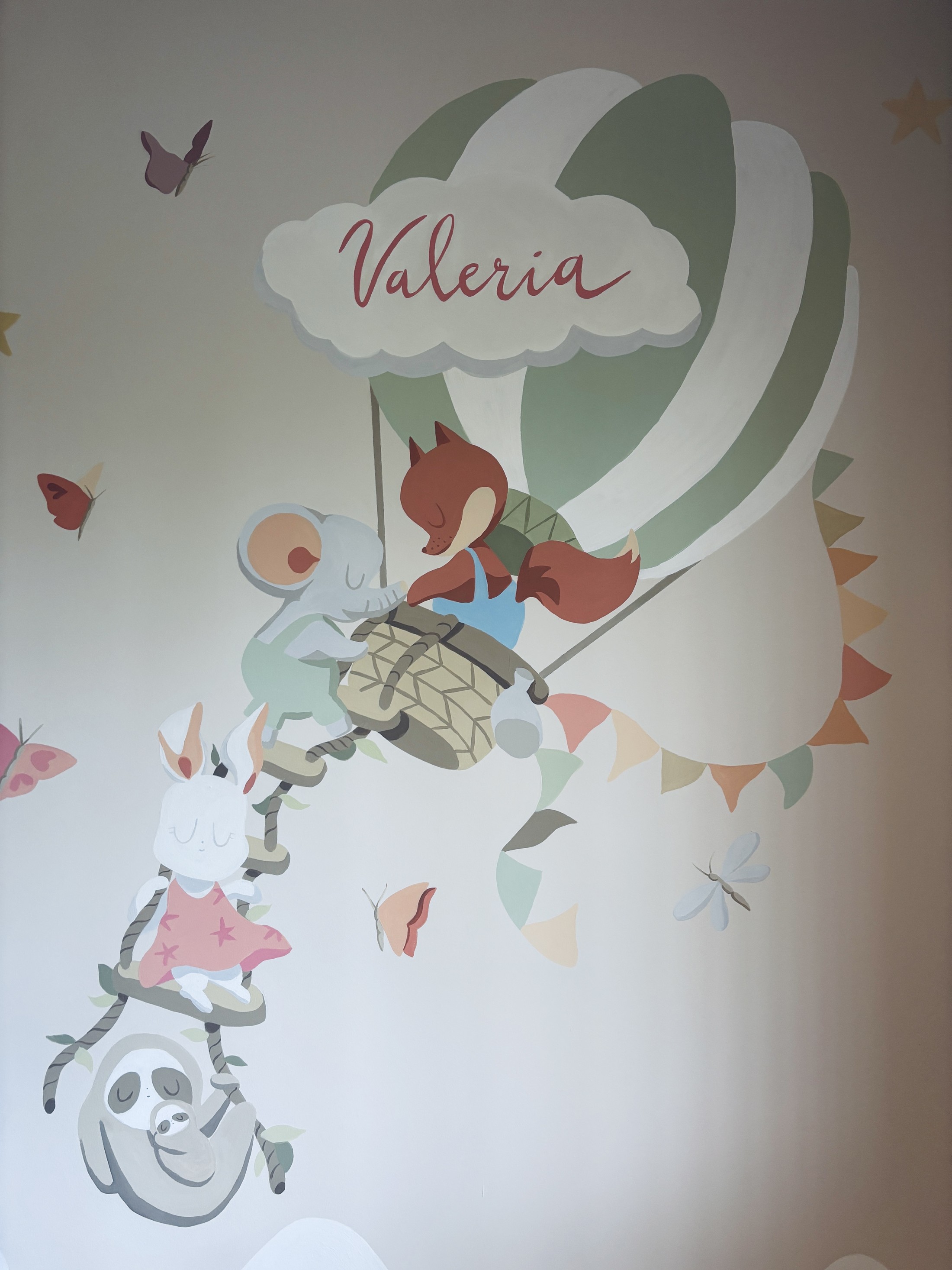 Mural infantil con globo aerostático y animales pintado en la habitación de un bebé