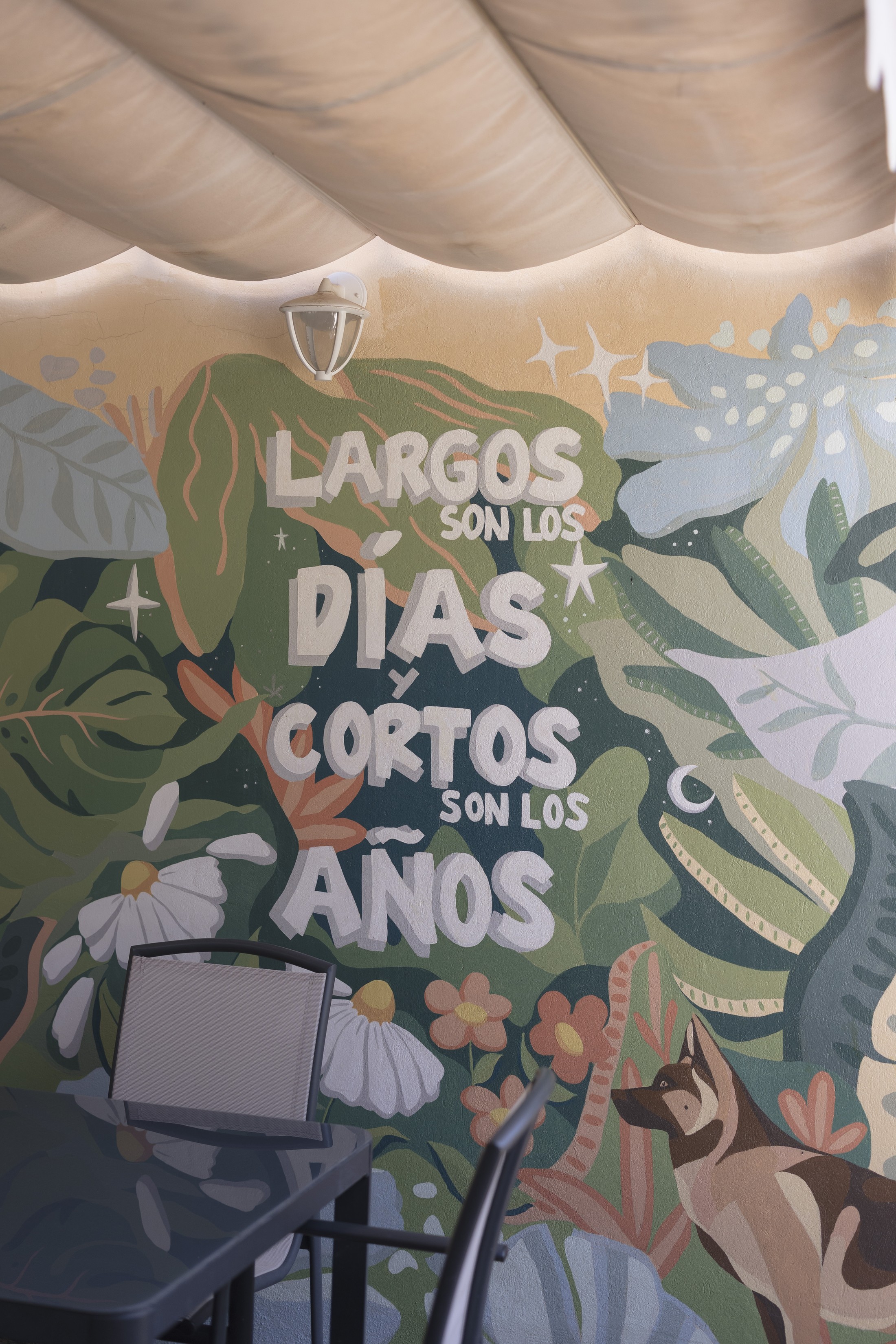 Mural botánico con la frase «Largos son los días y cortos son los años» en una terraza