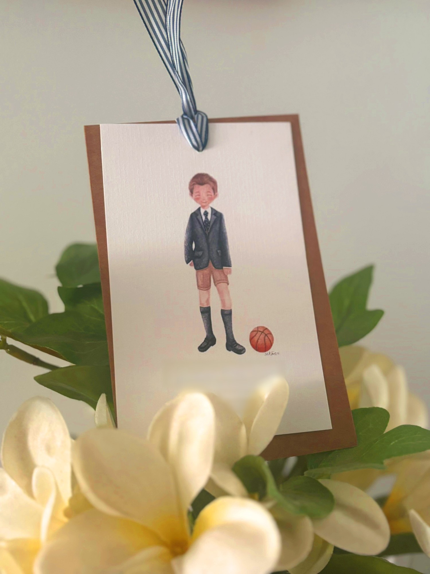 Recordatorio de comunión colgado con cinta, con un niño ilustrado junto a un balón de baloncesto