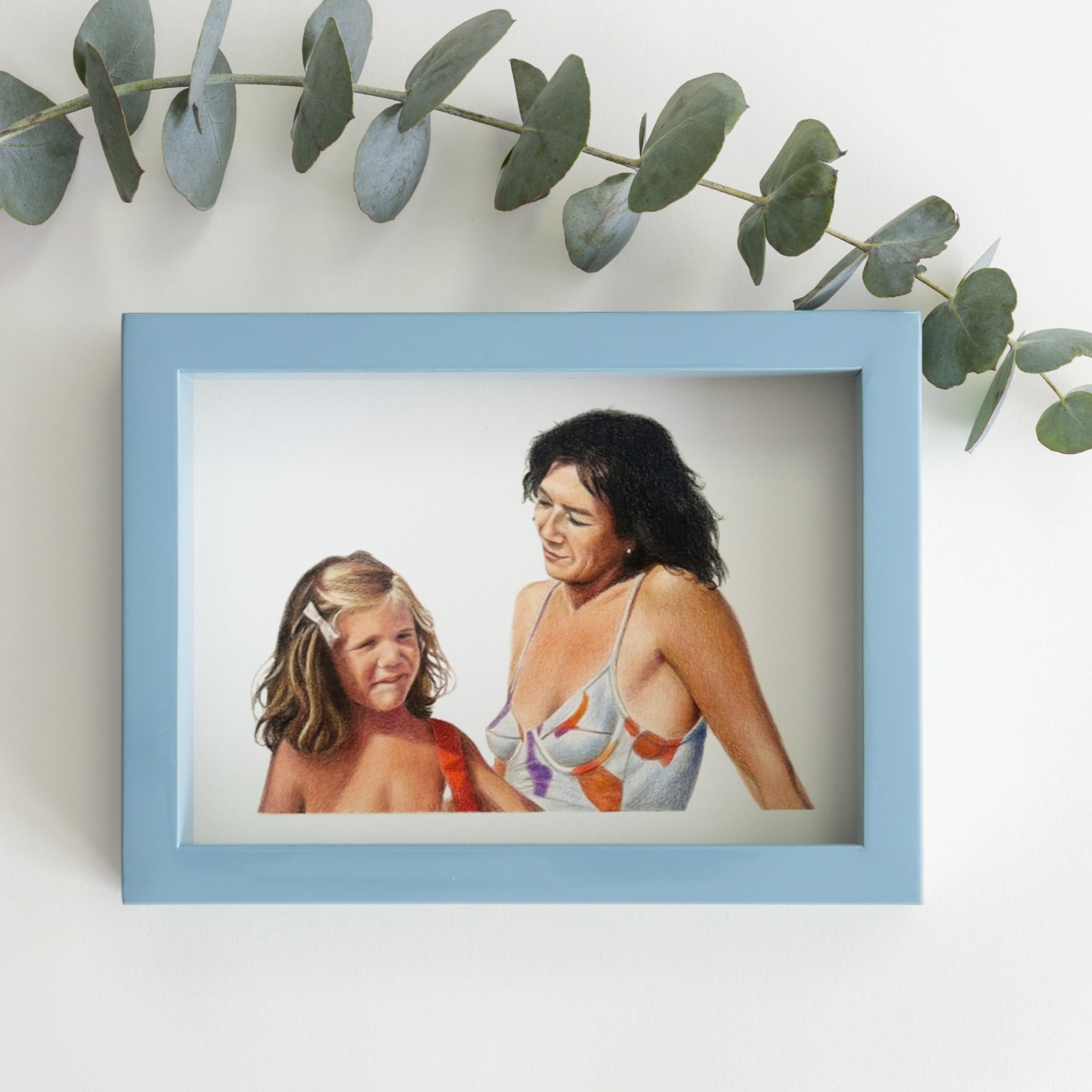 Retrato a color de una madre y su hija en la playa, en marco azul claro