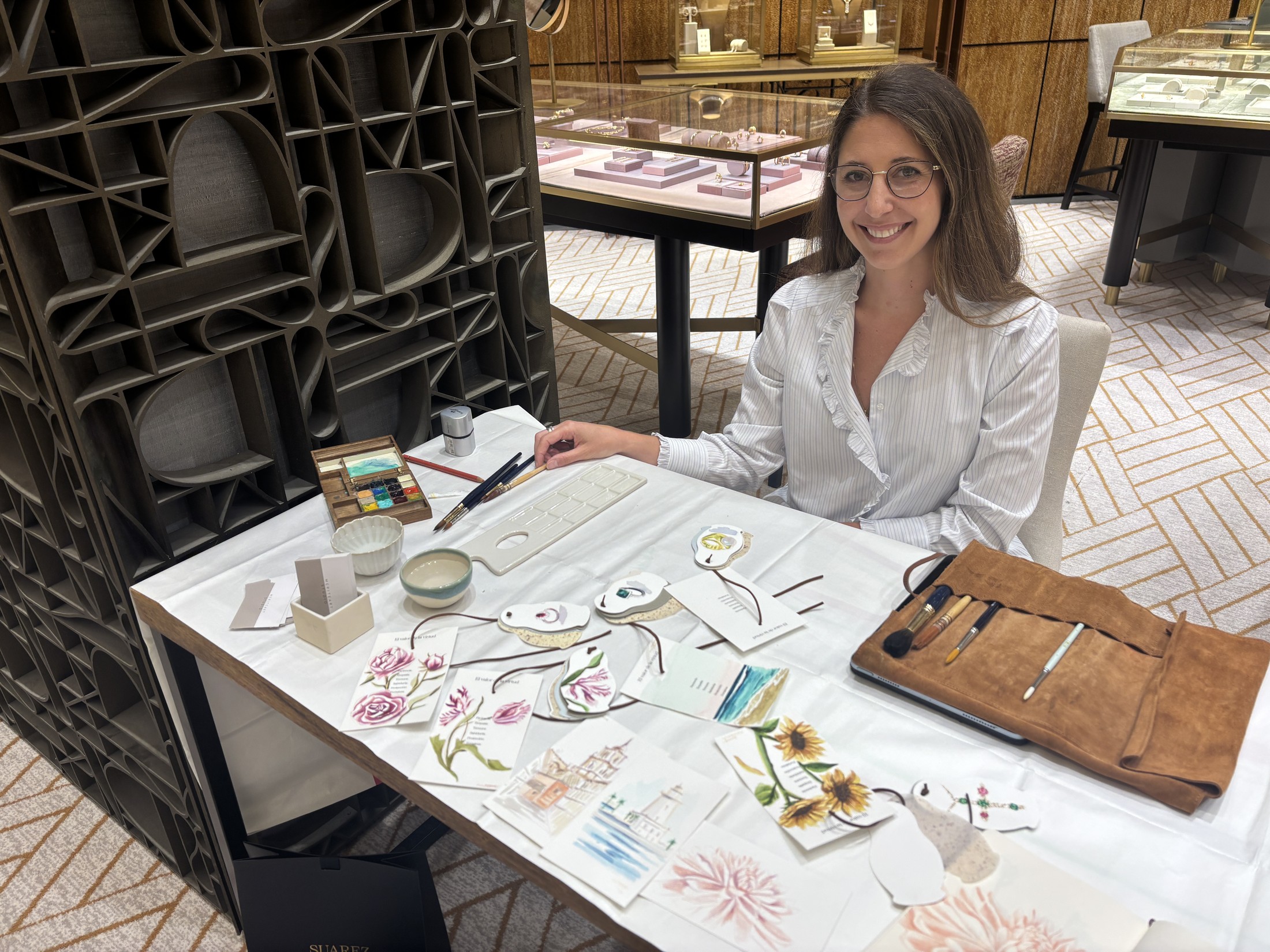 María Téllez durante el live painting en la joyería Suárez, con acuarelas de joyas sobre la mesa